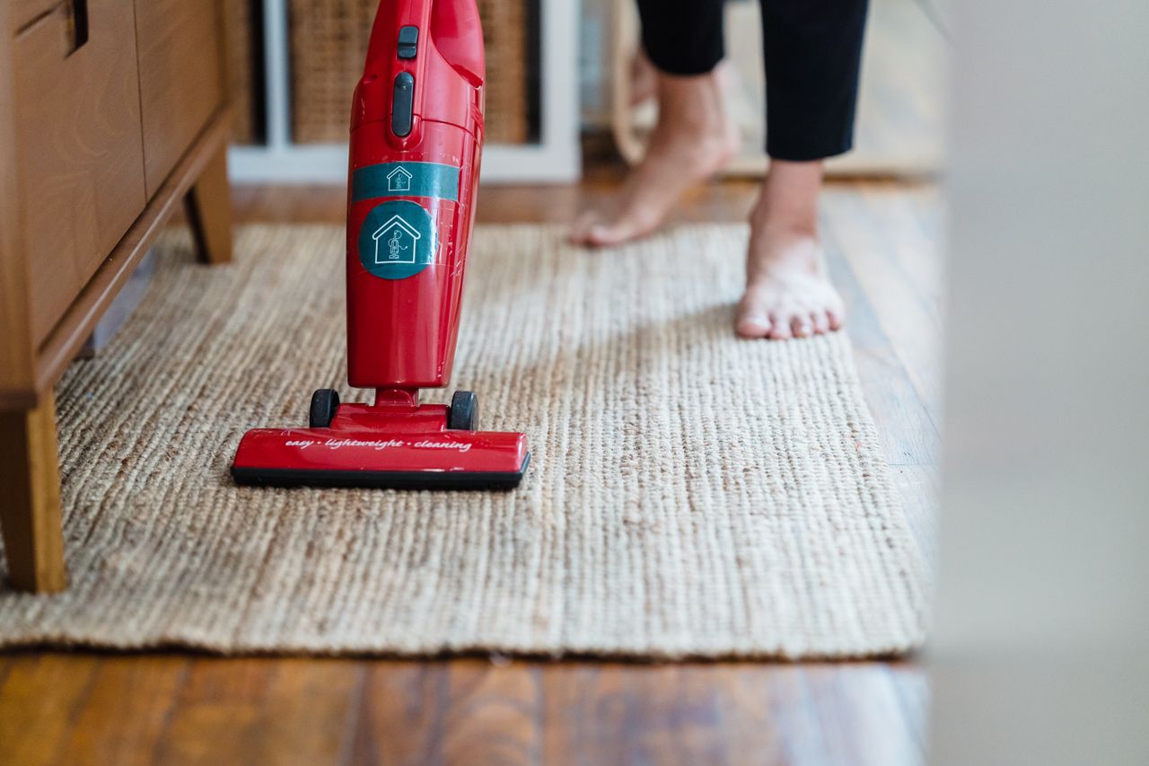 services-04 A red vacuum cleaner on a carpet in a stylish home setting with barefoot user.