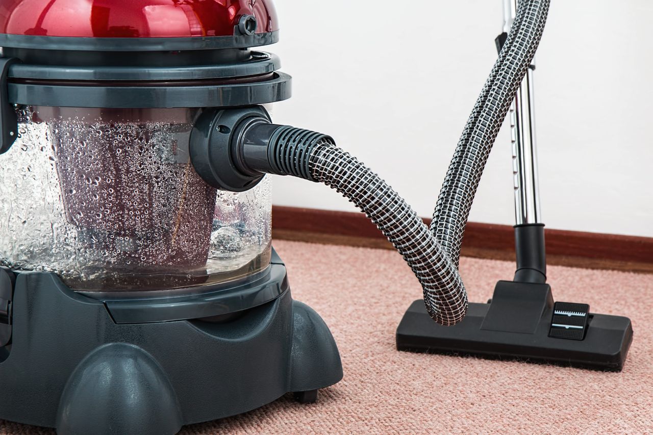services-03 Close-up of a modern vacuum cleaner with water filtration on carpet floor indoors.